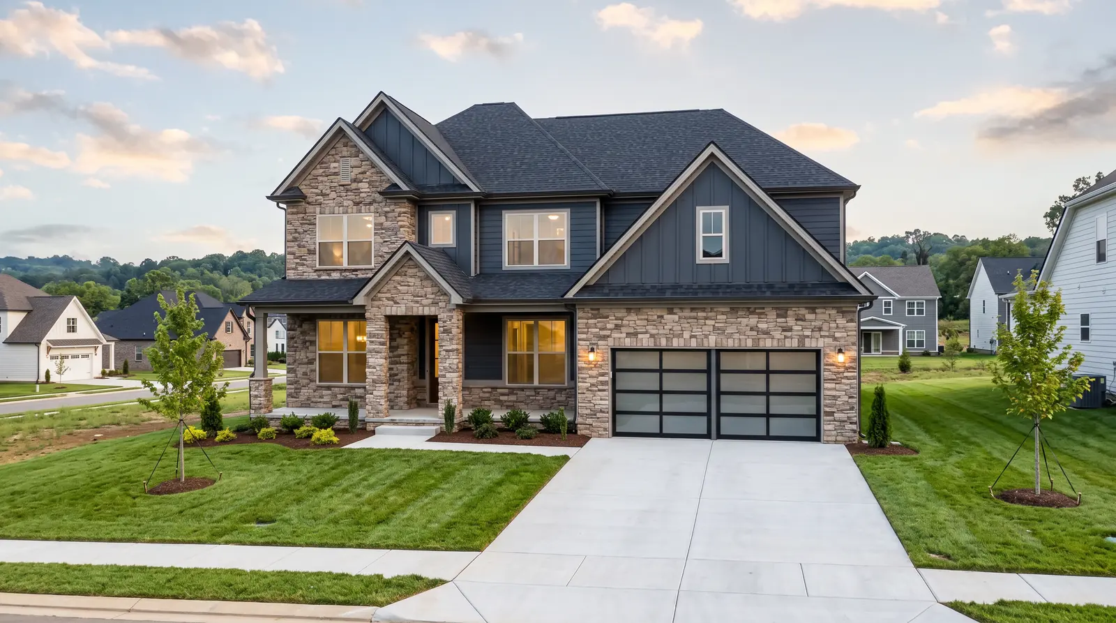 A newer two-story stone-and-siding home in a new Tennessee neighborhood with fresh sod and young trees, large clean windows and a tidy driveway
